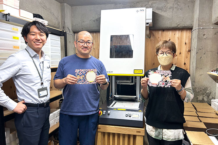 導入したレーザー加工機「SEIシリーズ EASY」の前に立つ、感通寺の皆様とコムネット営業担当の松井